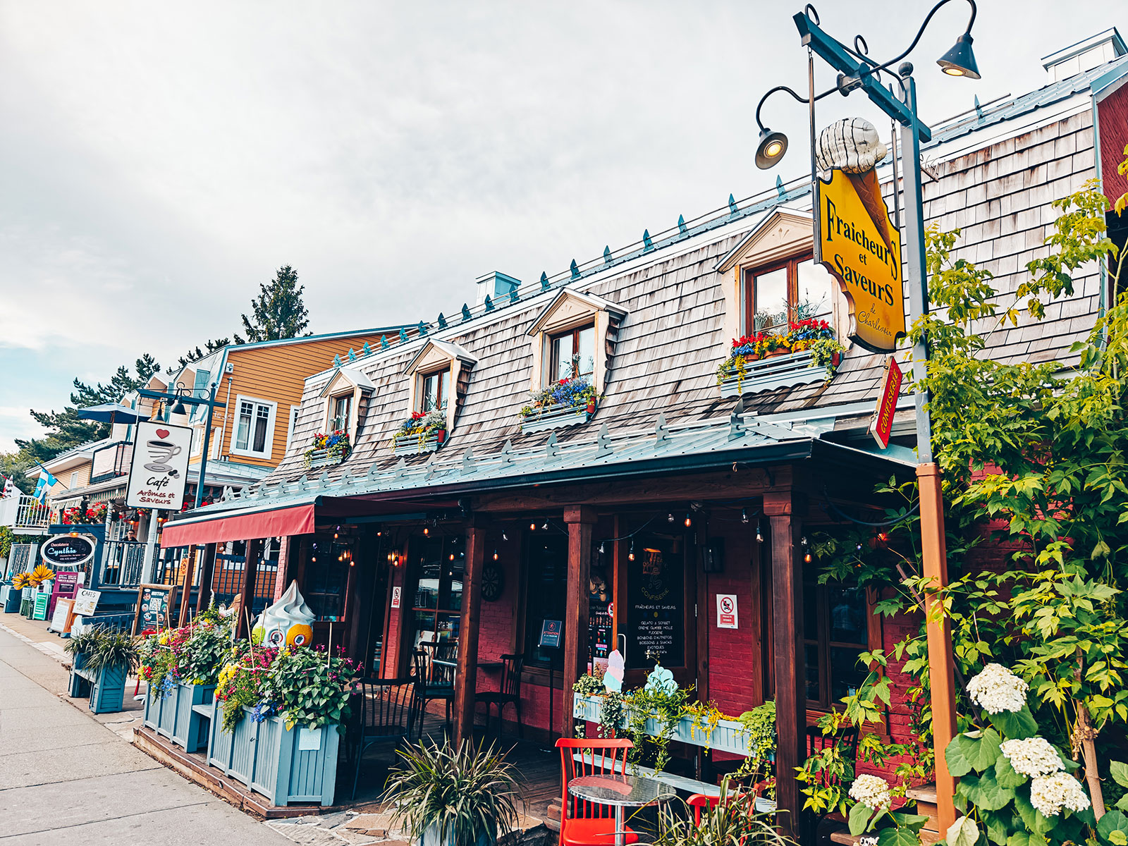 Une rue de boutiques avec terrasses et enseignes suspendues
