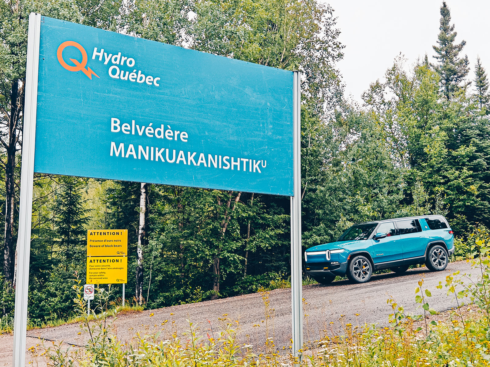 Le panneau bleu Hydro-Québec du belvédère Manikuakanishtiku au bord de la route, le Rivian stationné derrière