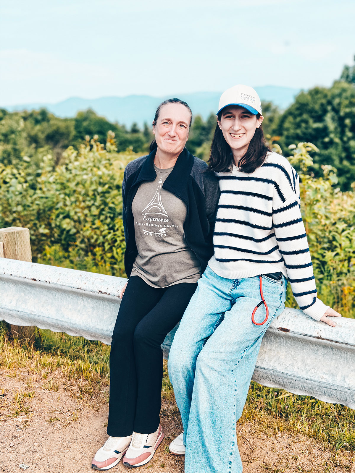 Deux femmes souriantes appuyées contre une glissière de sécurité