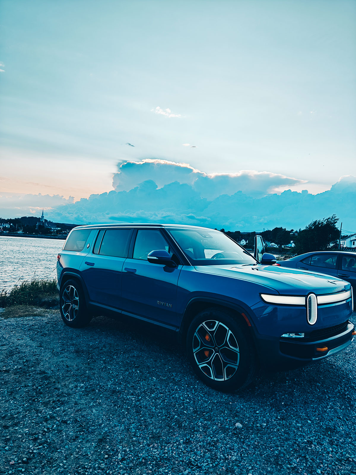 Le Rivian garé au bord de l’eau dans la lumière du soir