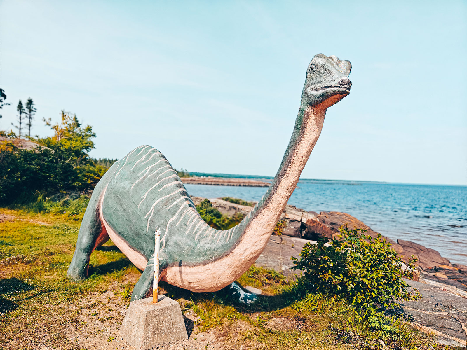 Sculpture de dinosaure dressée au bord de l'eau