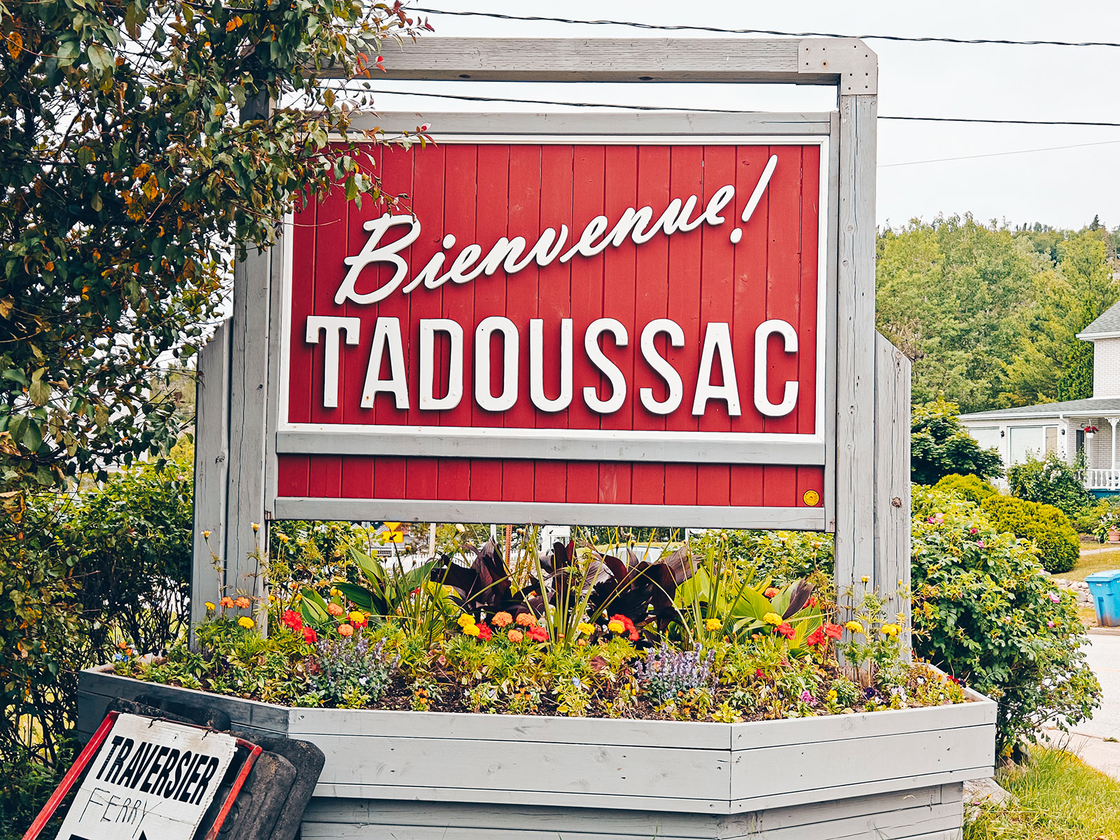 Le panneau « Bienvenue à Tadoussac » au milieu des fleurs