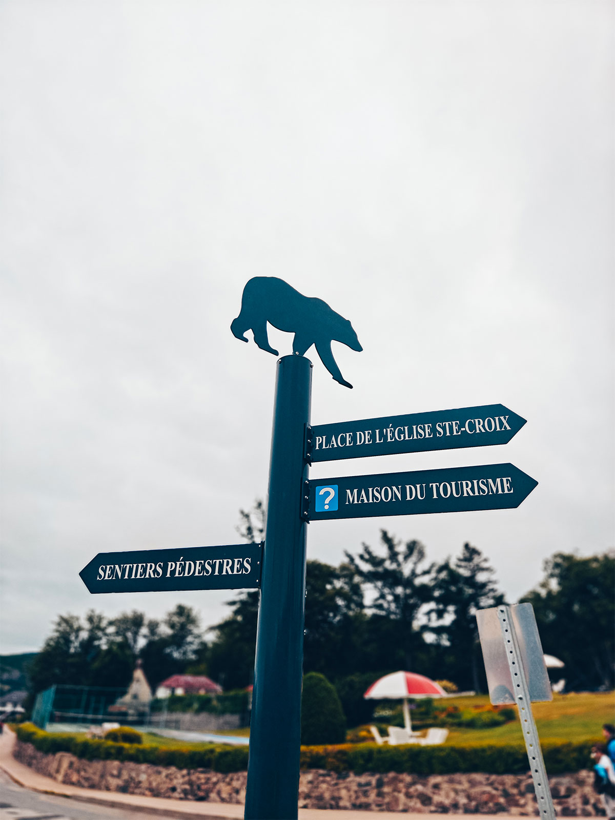 Un poteau indicateur surmonté d’un ours sculpté