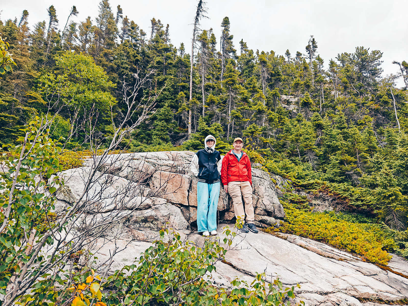 Deux personnes assises sur les rochers, la forêt derrière