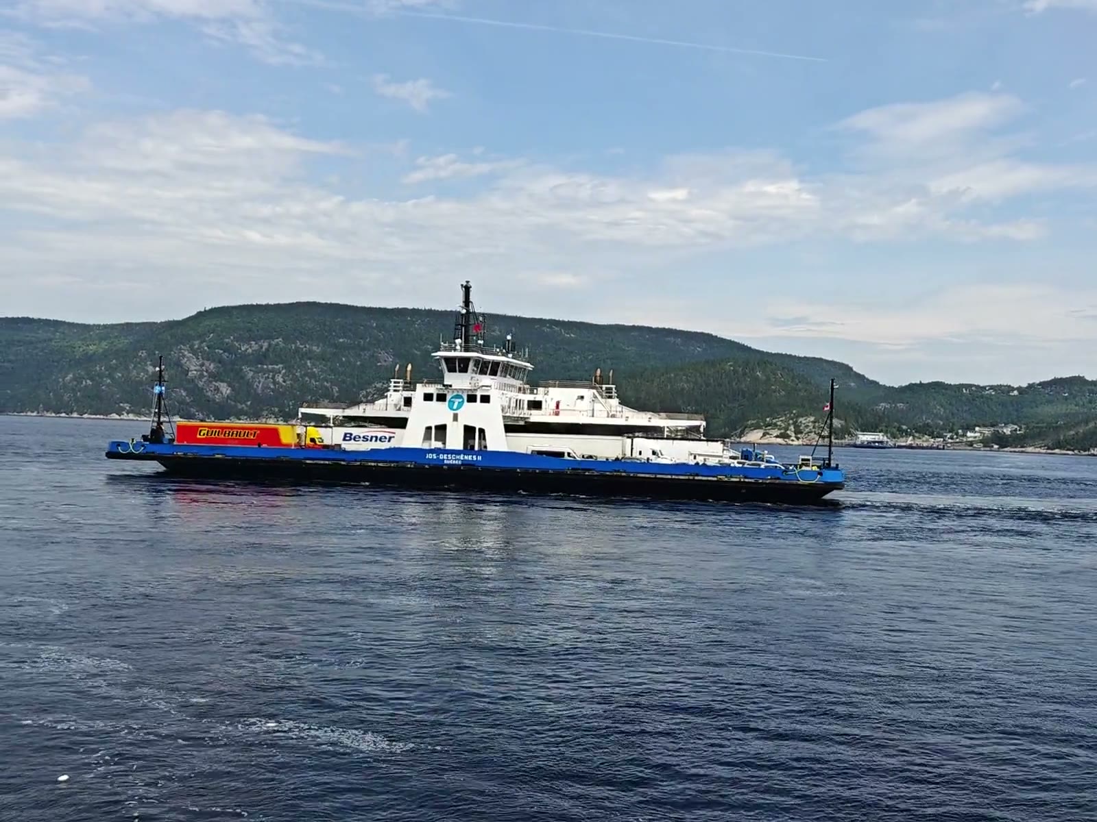 Le traversier bleu et blanc en navigation, son pont chargé de semi-remorques