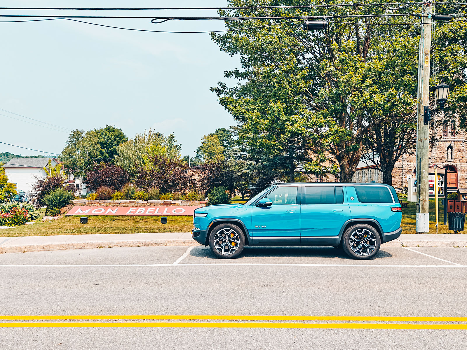 Vue panoramique du Rivian R1S bleu stationné dans une rue du village de Montebello