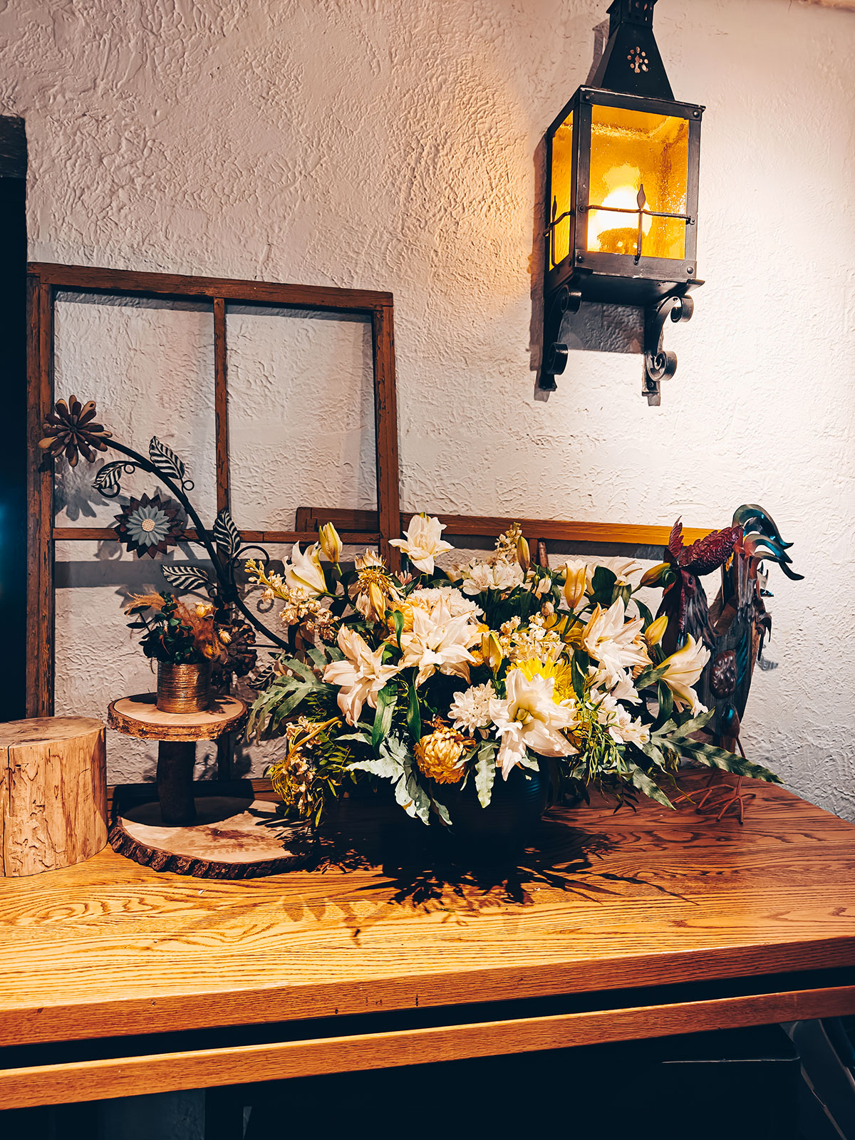 Un bouquet posé sur une table de bois, une lanterne accrochée au mur de billes