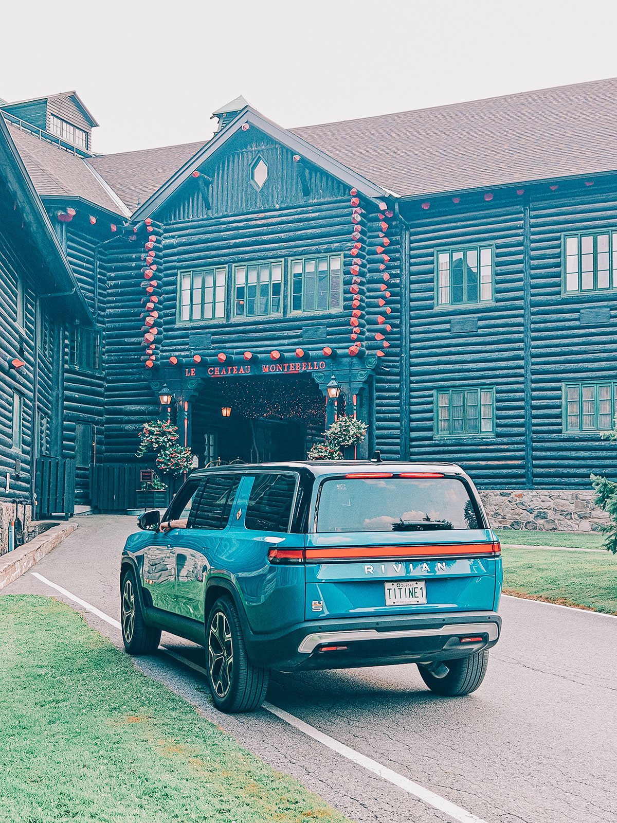 Le Rivian R1S bleu roulant le long de la façade en bois rond