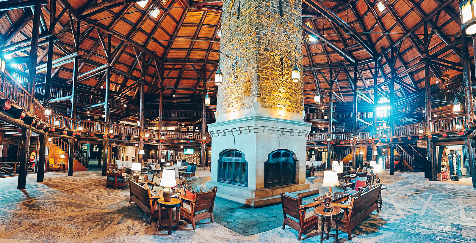 Vue panoramique du grand hall, sa cheminée de pierre et sa charpente apparente