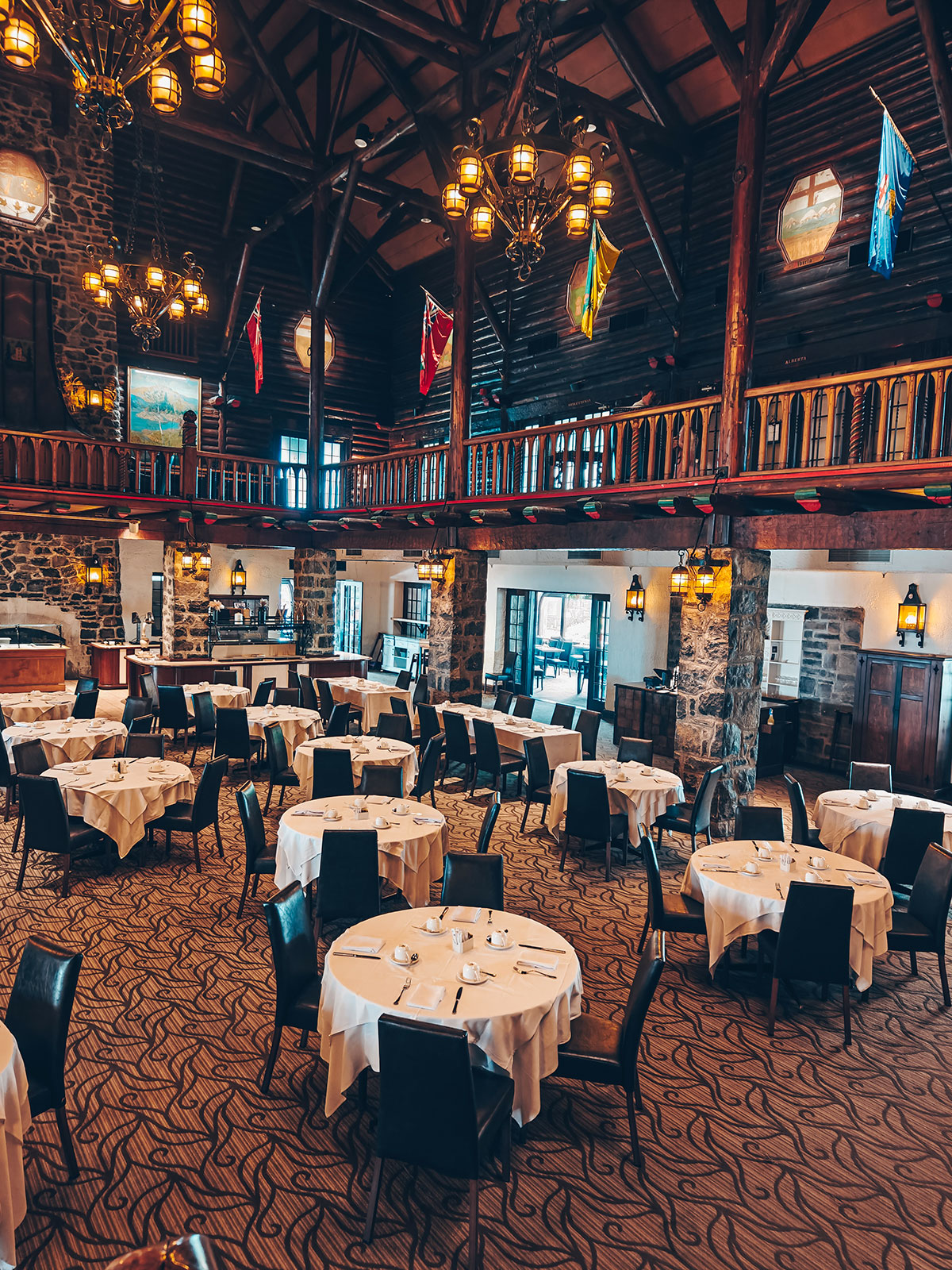La salle à manger, ses tables rondes nappées de blanc et les drapeaux de la galerie