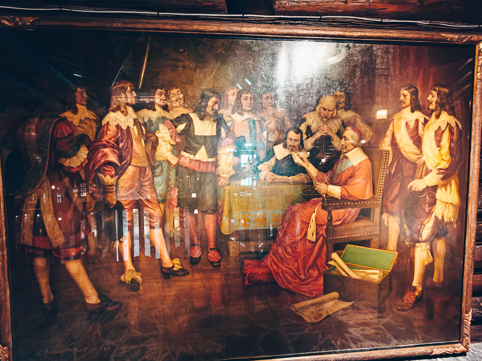 Un grand tableau ancien représentant une scène de colons, une femme en robe rouge au centre