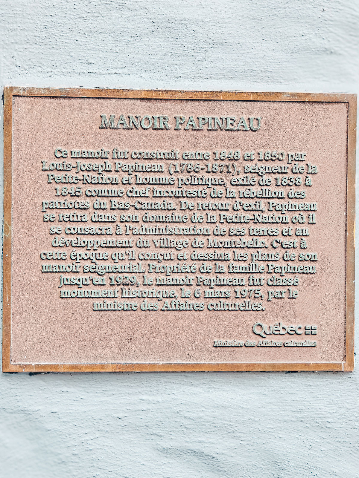La plaque commémorative « Manoir Papineau », scellée dans le mur blanc