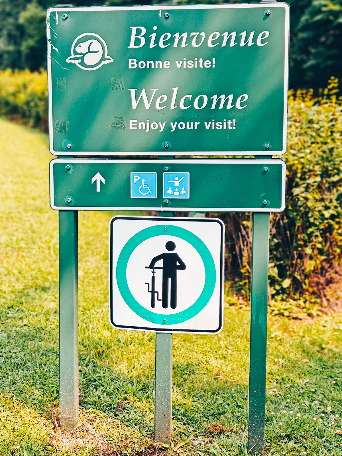 Le panneau vert « Bienvenue · Bonne visite! / Welcome · Enjoy your visit! »
