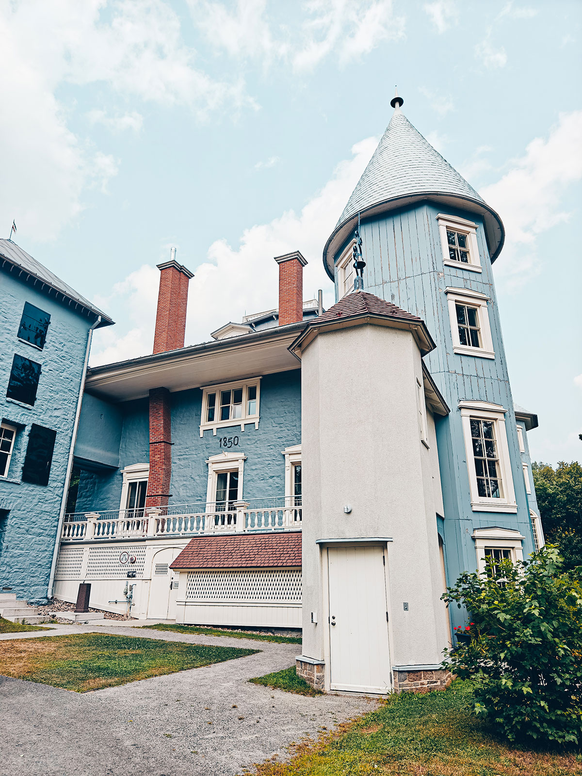 Le manoir vu de face : lambris gris-bleu, galerie blanche et tour ronde
