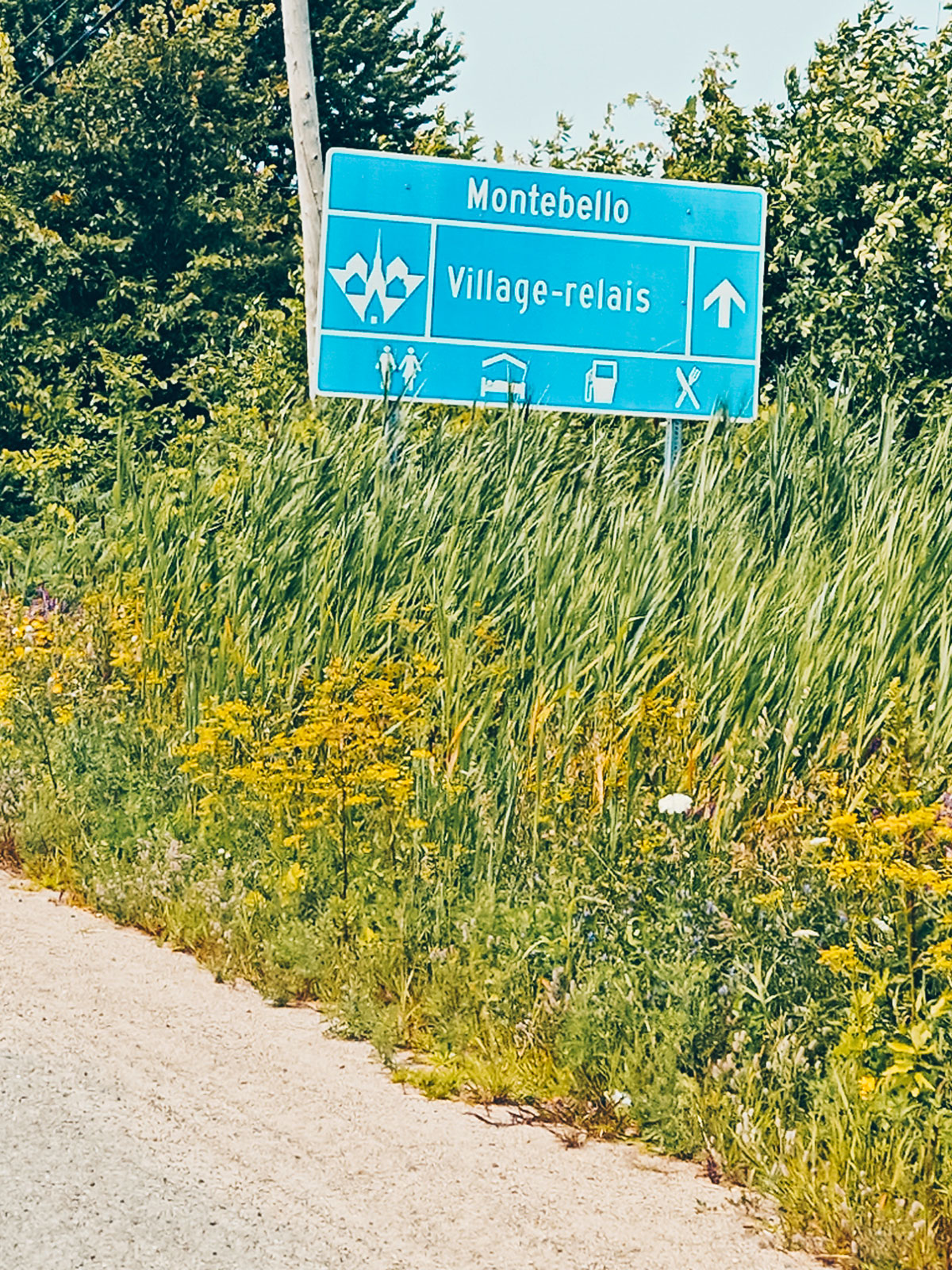 Le panneau bleu « Montebello · Village-relais » et ses pictogrammes de services