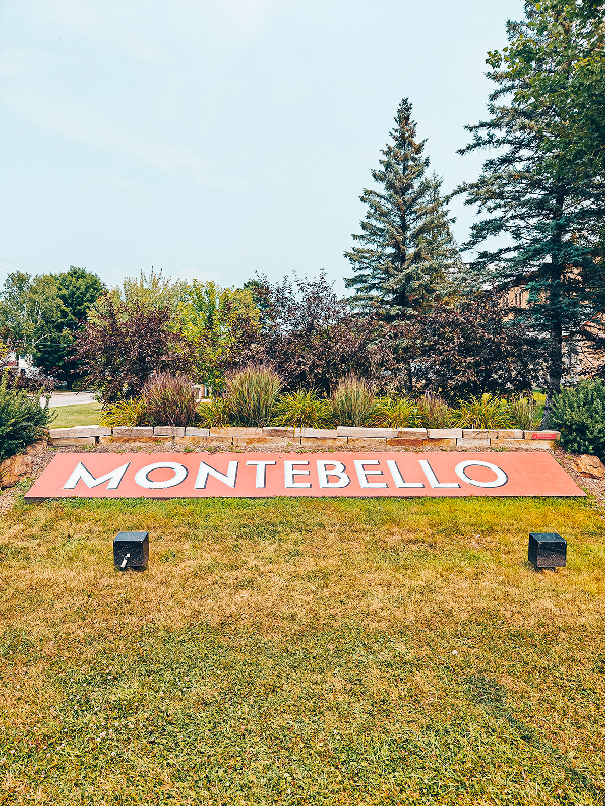 De grandes lettres orange formant le mot MONTEBELLO, posées sur la pelouse