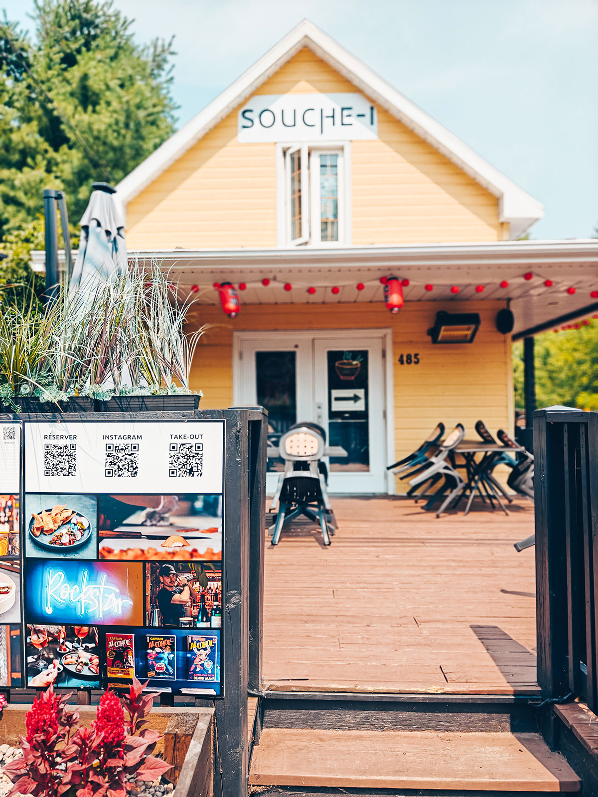 Une boutique jaune à terrasse de bois, décorée de fleurs