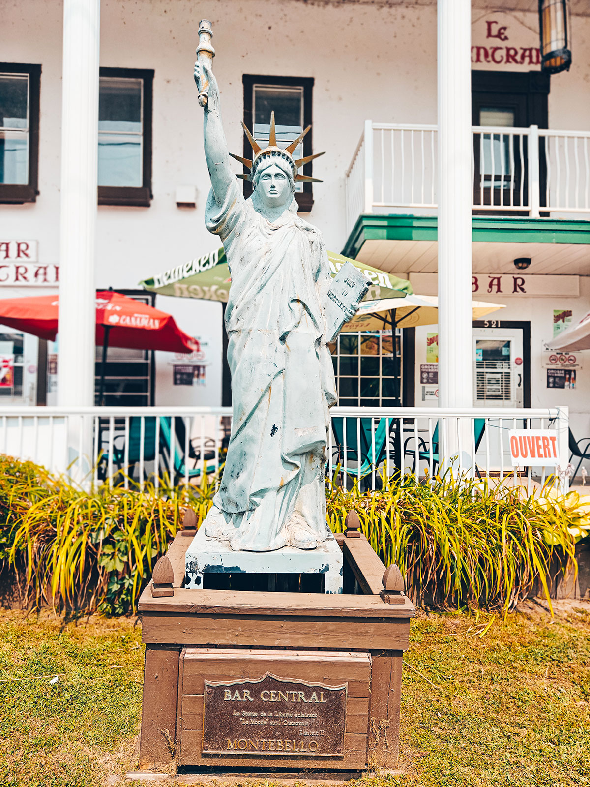 Une petite statue de la Liberté sur son socle, devant un bar du village