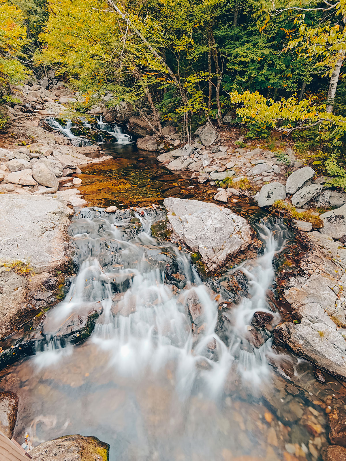 L'eau dévale les dalles de granit entre les feuillages d'automne