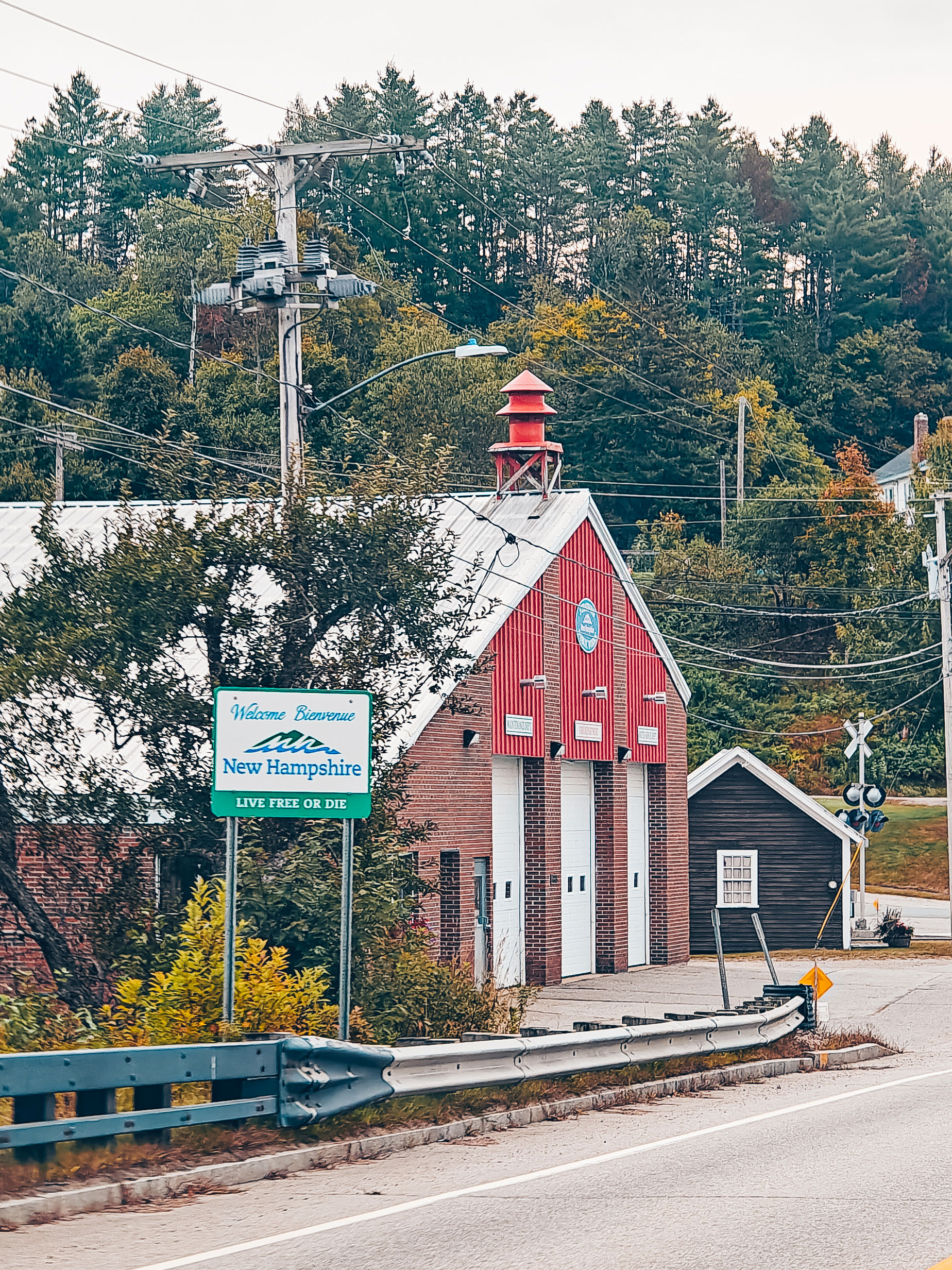 Une rue de village avec un grand bâtiment rouge et le panneau d'entrée du New Hampshire