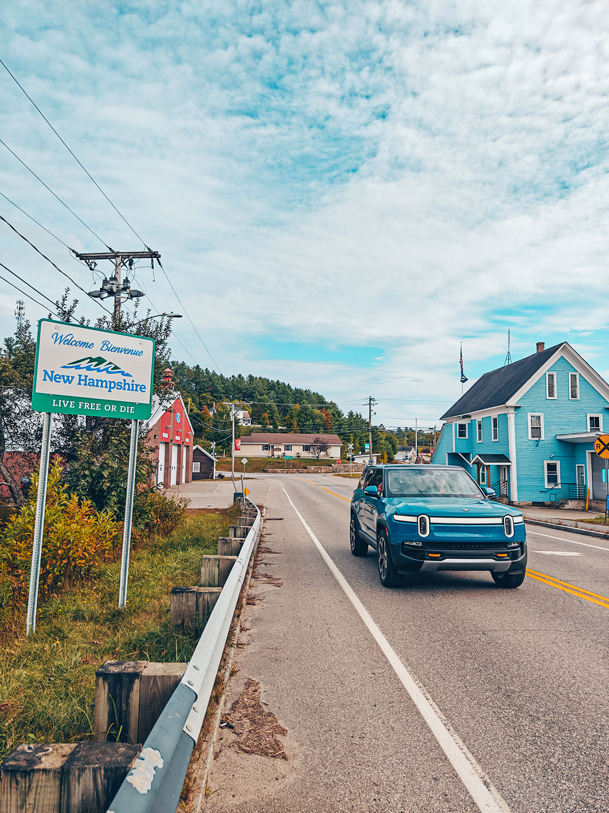 Le Rivian sur la route d'un village, devant le panneau « Welcome to New Hampshire »