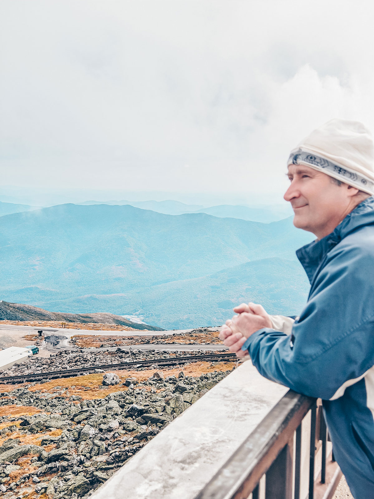 Un homme en tuque regarde les montagnes depuis le sommet