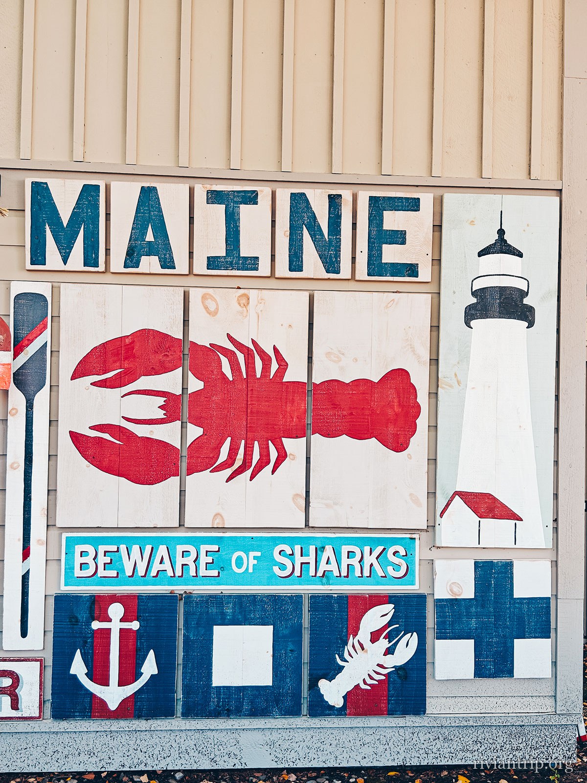 Une murale « MAINE · Beware of sharks », homard et phare peints