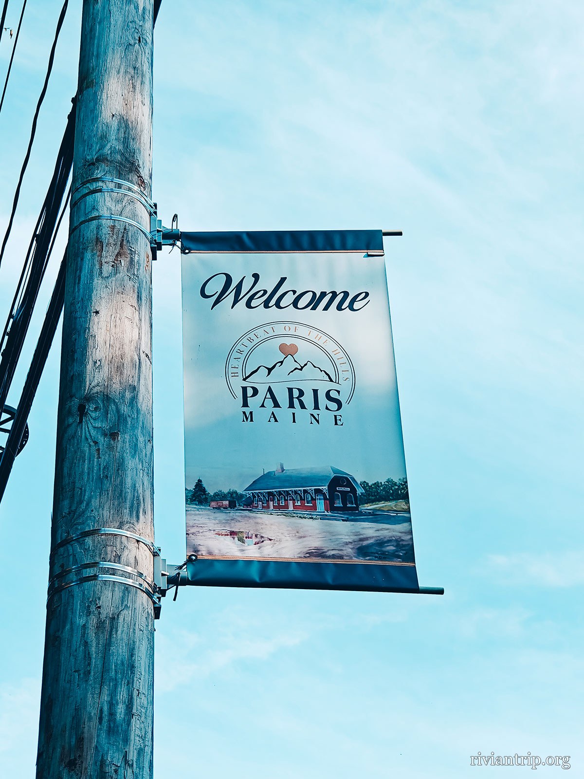 Une bannière de rue « Welcome · Paris » accrochée à un lampadaire