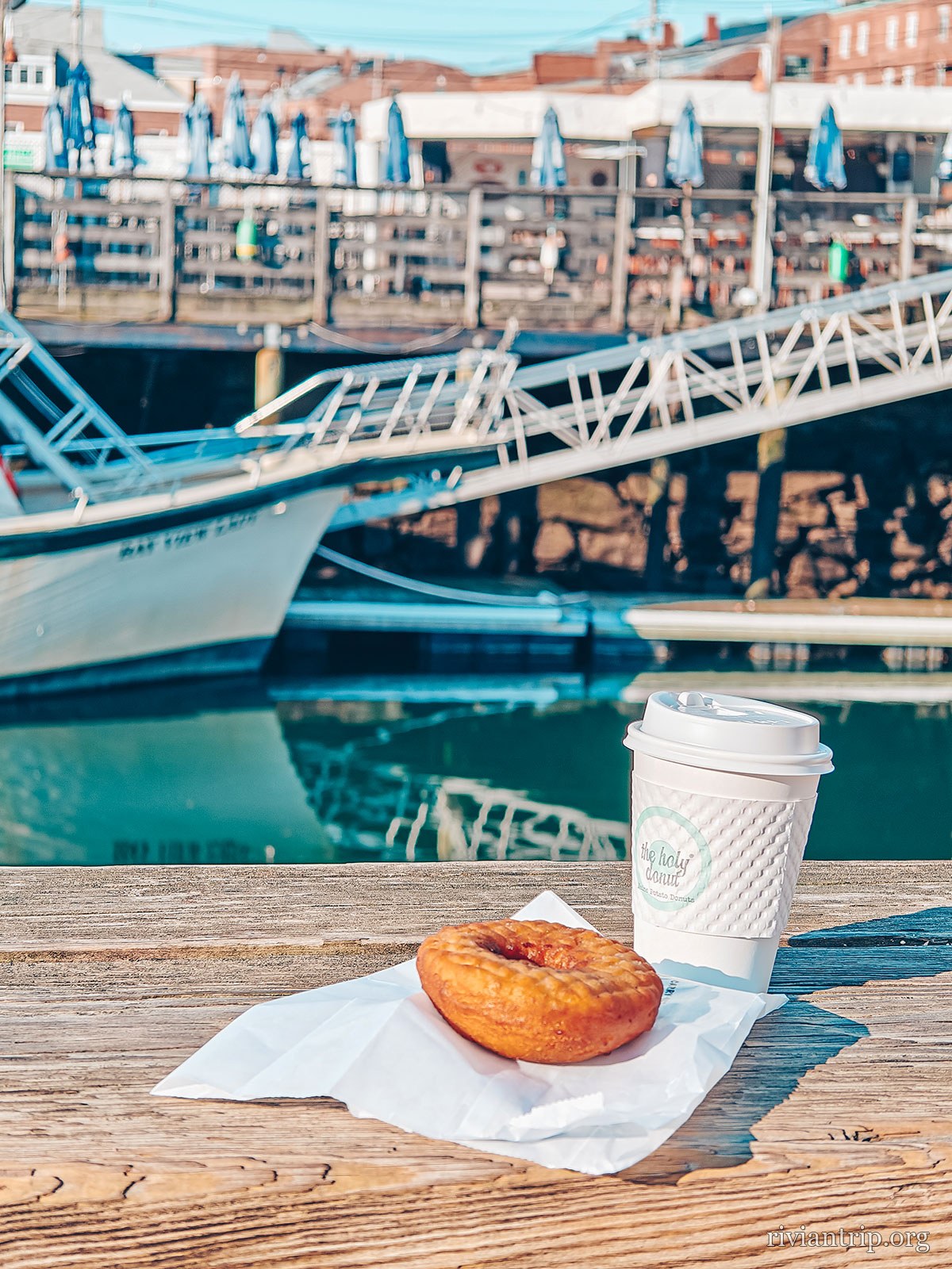 Un café et un beignet posés sur une table, face au port