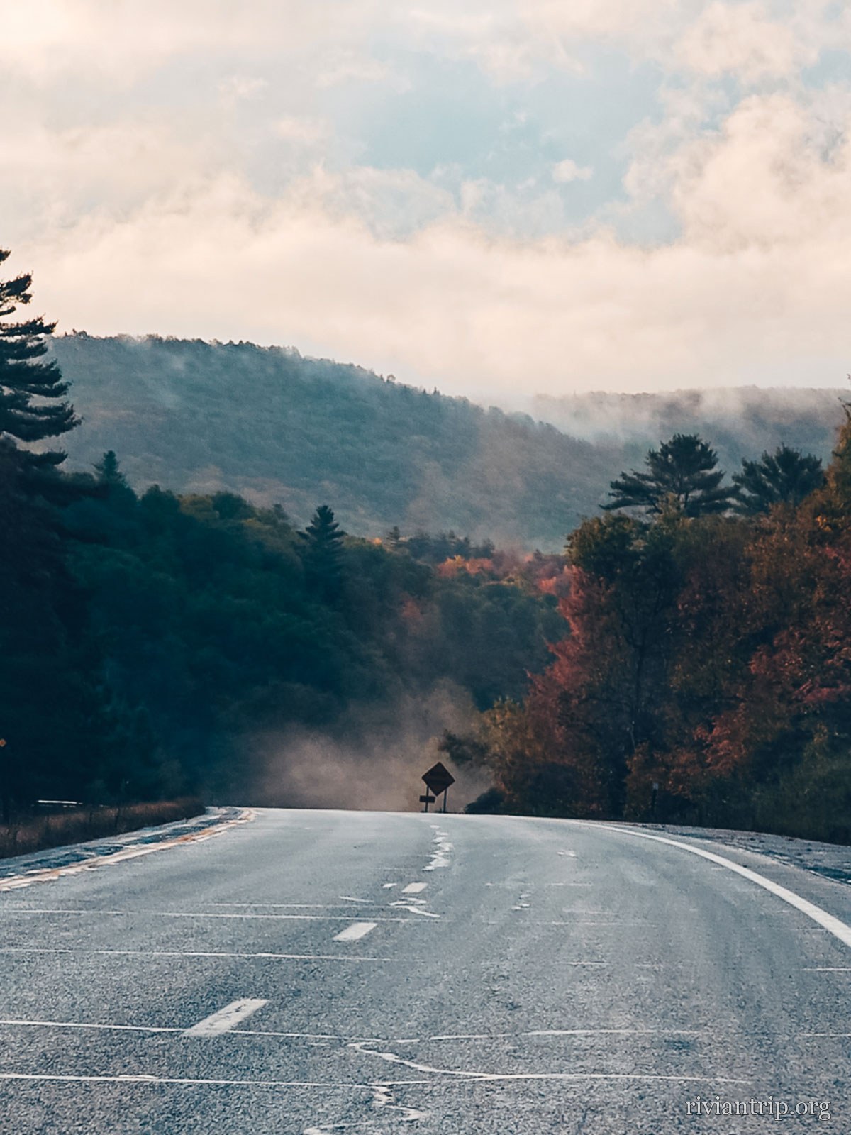 La route qui plonge vers une vallée noyée de brume