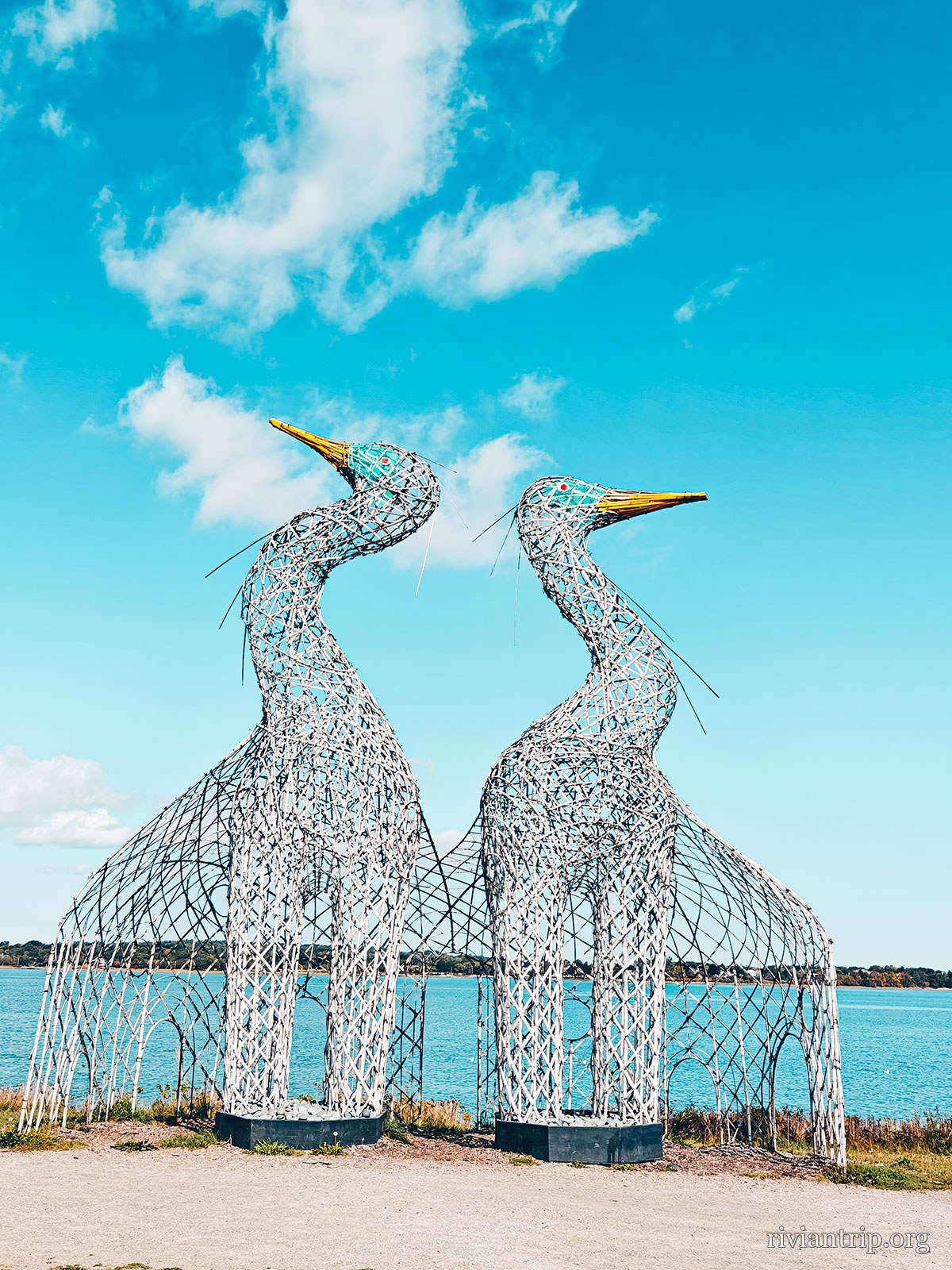 Deux grands hérons de métal ajouré dressés face à la baie